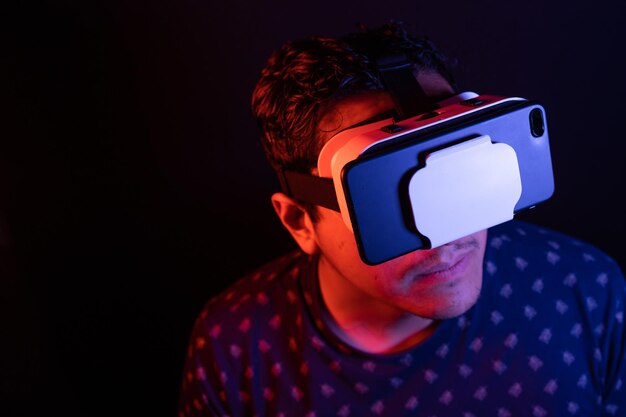 Joven latino usando Realidad Virtual VR Auriculares Gafas 3D Fondo oscuro Clave baja