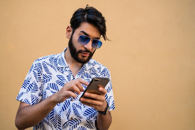 Joven latino usando su teléfono móvil