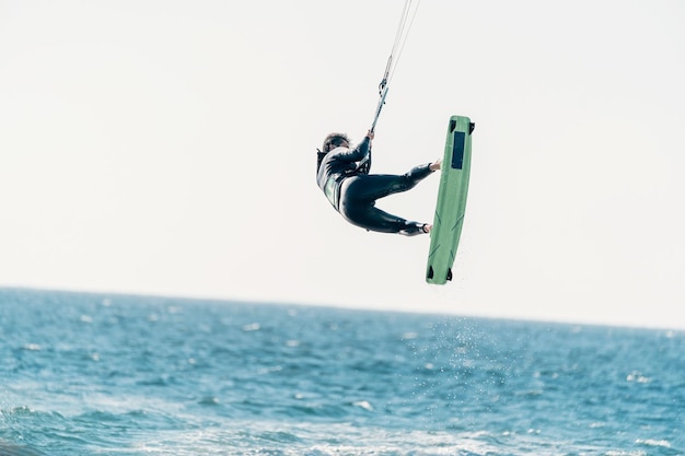 Joven latino volando en el aire haciendo kitesurf o kitesurf