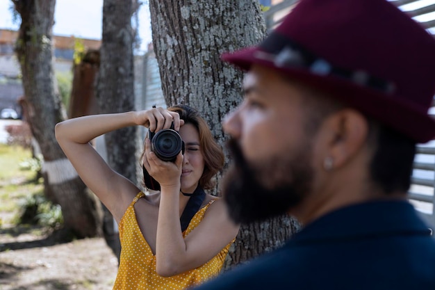 Joven latinoamericana con cámara en mano toma fotos de su pareja de vacaciones Caminando y concepto de vacaciones
