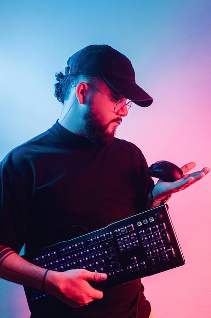 Joven latinoamericano con barba sosteniendo un teclado y un mouse para juegos