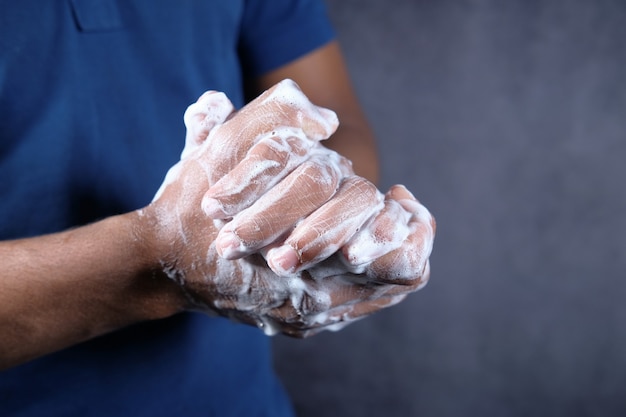 Foto joven lavarse las manos con agua tibia y jabón aislado en negro