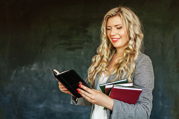 Una joven lee y tiene muchos libros.