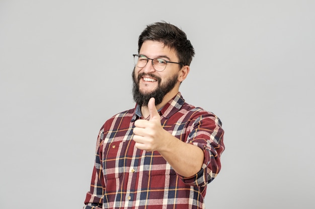 Joven levanta el pulgar. Aislado en gris