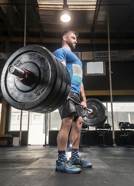 Foto un joven levantando barras en un gimnasio bien iluminado