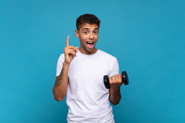 Joven levantando una campana sintiéndose como un genio feliz y emocionado después de realizar una idea, levantando alegremente el dedo, ¡eureka!