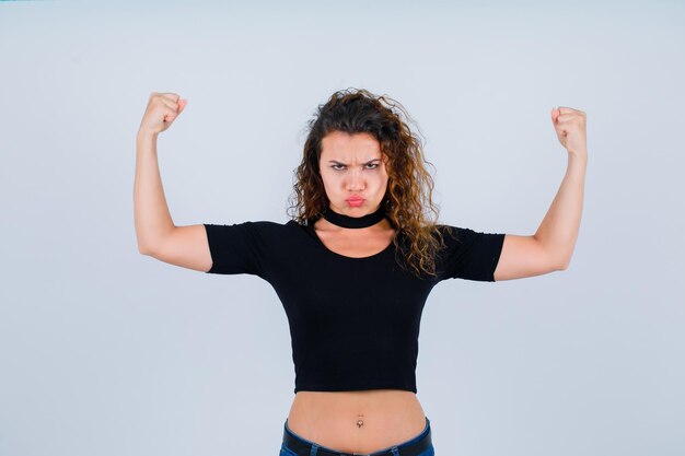 Foto la joven está levantando sus músculos sobre fondo blanco.