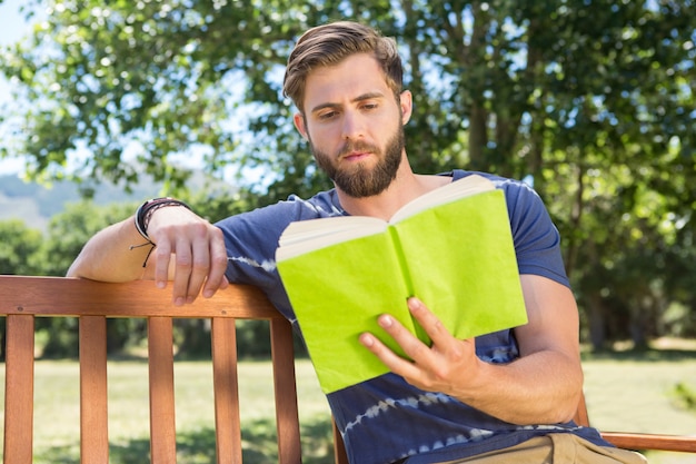 Joven leyendo en el banco del parque