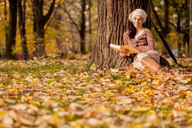 Joven leyendo en el bosque de otoño