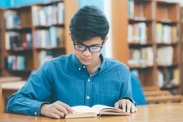 Joven leyendo un libro en la biblioteca pública