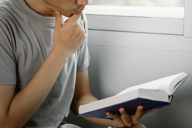 Joven leyendo un libro mientras está en casa