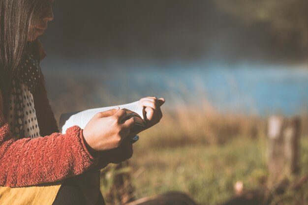 Joven leyendo un libro en el parque natural con frescura en la mañana