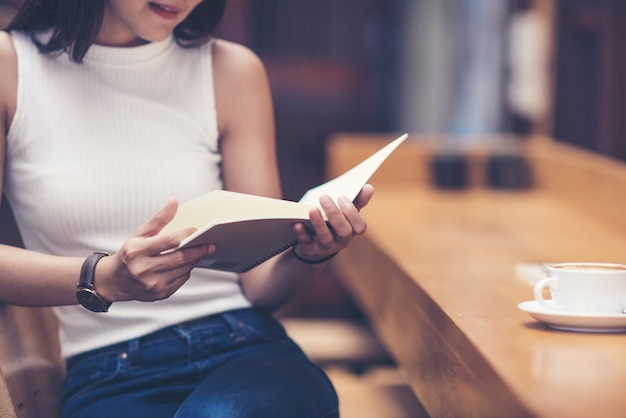 Joven leyendo un libro con una taza de café