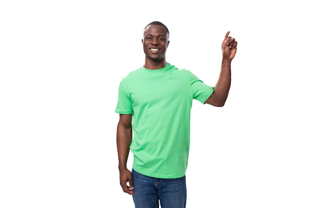 Joven líder africano vestido con una camiseta verde y jeans gesticulando activamente sobre un blanco