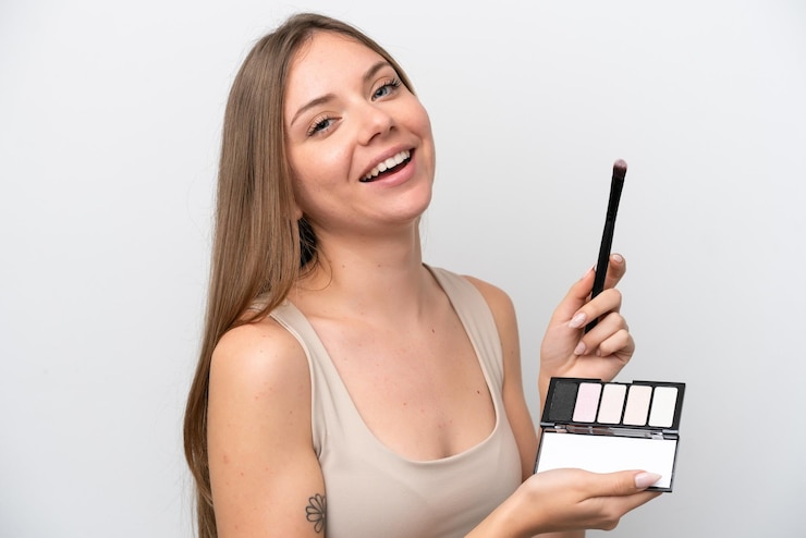 Foto joven lituana aislada de fondo blanco con paleta de maquillaje y feliz