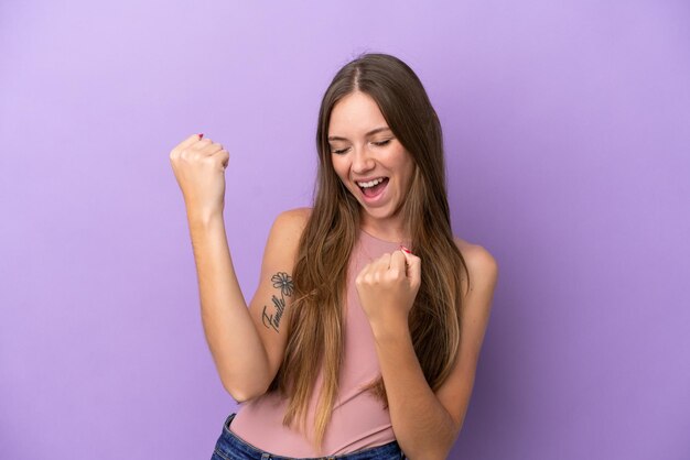 Joven lituana aislada de fondo morado celebrando una victoria