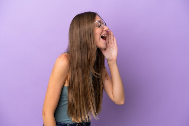 Joven lituana aislada de fondo morado gritando con la boca abierta a un lado