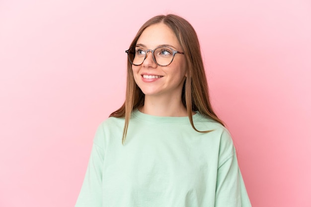 Joven lituana aislada de fondo rosa Con gafas con expresión feliz