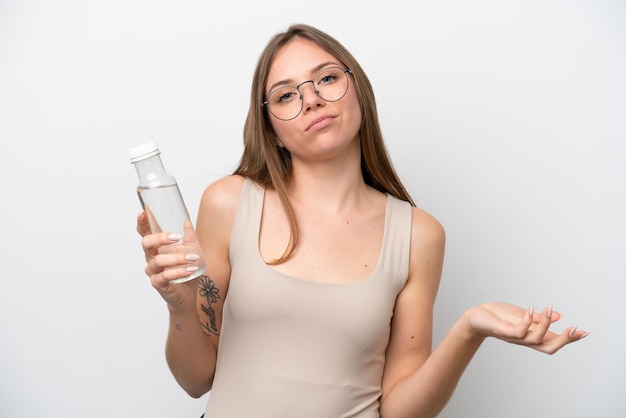 Joven lituana con una botella de agua aislada de fondo blanco haciendo gestos de duda mientras levanta los hombros