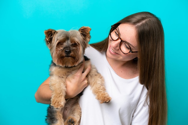 Joven lituana sosteniendo un perro aislado de fondo azul