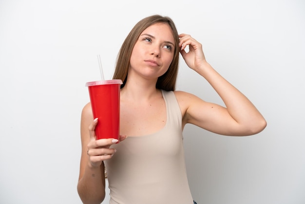 Joven lituana sosteniendo un refresco aislada de fondo blanco con dudas y con una expresión facial confusa