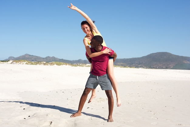 Joven llevando novia de espaldas en la playa