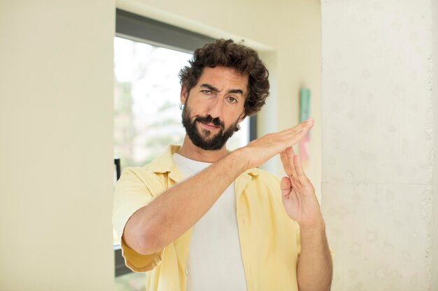 Foto joven loco barbudo que parece serio, severo, enojado y disgustado haciendo señal de tiempo de espera