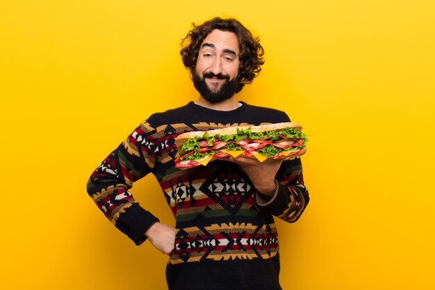 Joven loco barbudo con un sándwich gigante.