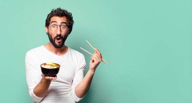 Joven loco barbudo con un tazón de ramen de fideos