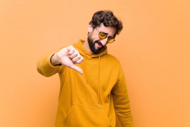 Joven loco cool hombre triste expresión en pared naranja