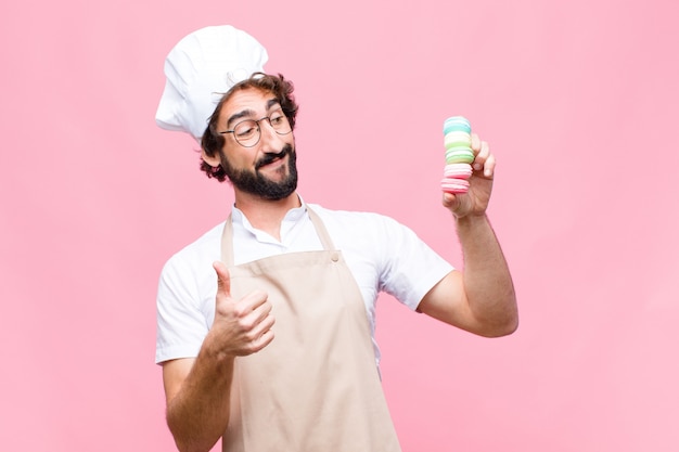 Joven loco fresco con macarons contra pared rosa