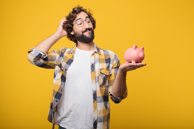 Joven loco loco tonto pose con una alcancía. concepto de ahorro