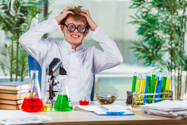 Foto joven loco químico trabajando en el laboratorio