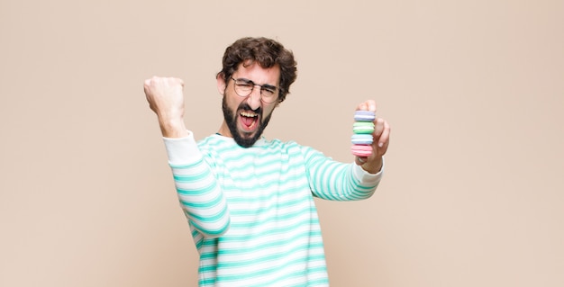 Foto joven con macarrones contra la pared plana