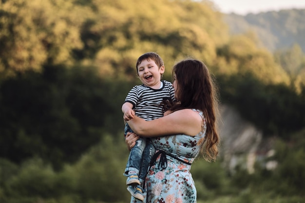 La joven madre abraza a su hijo con fuerza y él se ríe de placer y vergüenza