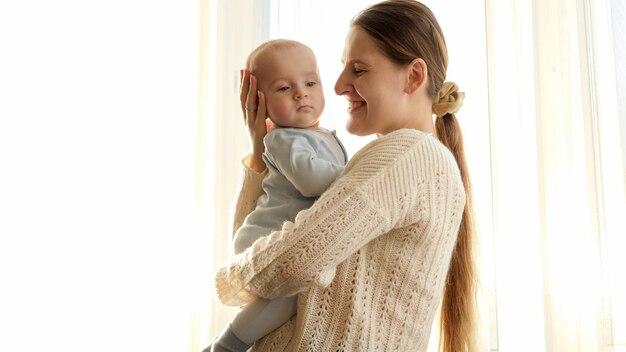 Foto joven madre abrazando y sonriendo a su pequeño hijo a la luz del atardecer concepto de felicidad familiar y crianza de los hijos