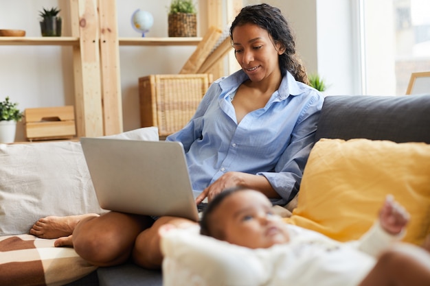 Joven madre africana trabajando en casa