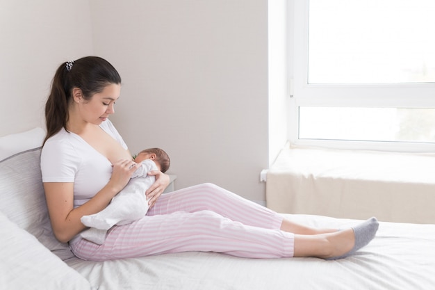 Joven madre amamantando, amamantando y abrazando al bebé