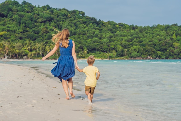 Joven madre amorosa y su pequeño hijo jugando en la playa