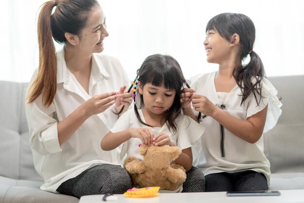 Joven madre asiática atando el cabello de su hija