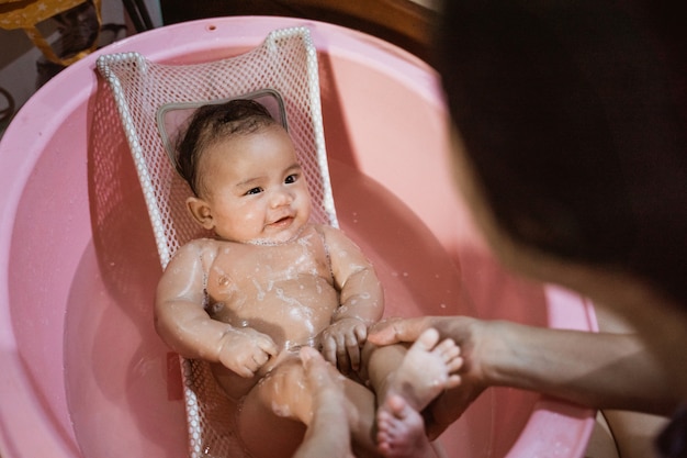 Joven madre asiática bañando a su hija bebé