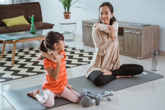 Joven madre asiática haciendo ejercicio de yoga en casa con su hija juntos