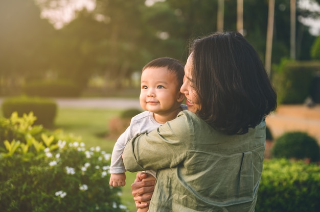 Foto joven madre asiática con su hijo o lindo bebé en el parque en casa.