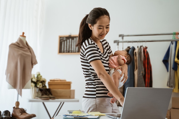 Joven madre asiática trabajando desde casa con su hija