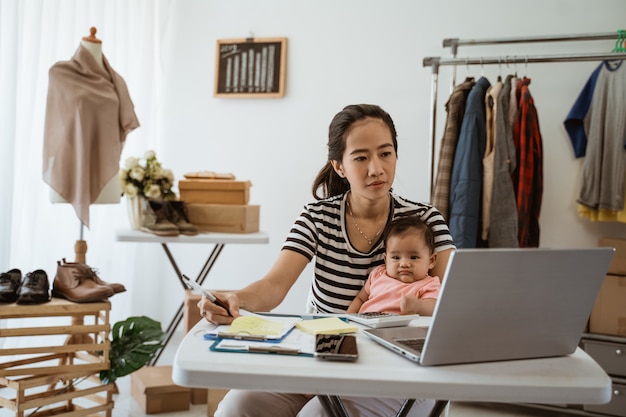 Foto joven madre asiática trabajando desde casa con su hija