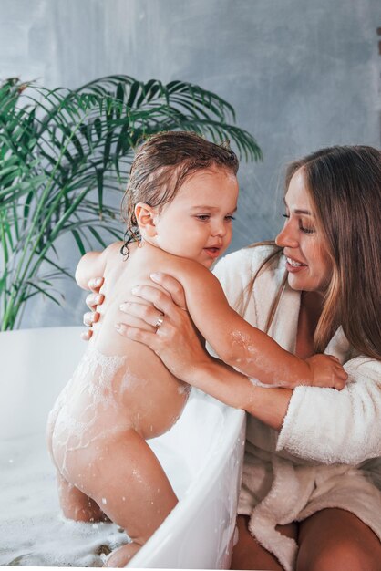 La joven madre ayuda a su hija a lavarse en el baño.