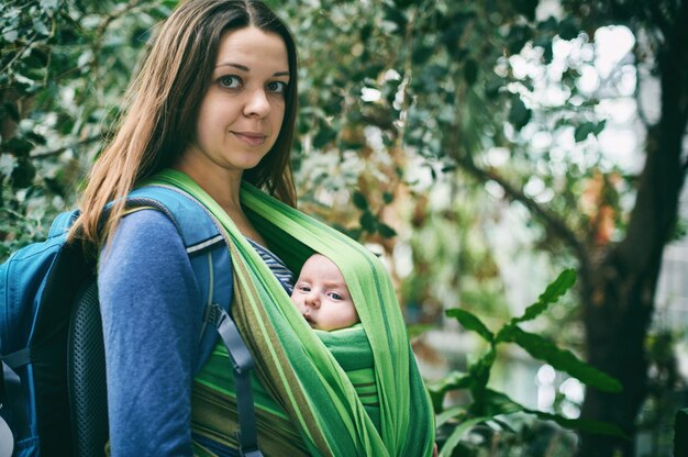 Una joven madre con un bebé en una honda está caminando en la jungla