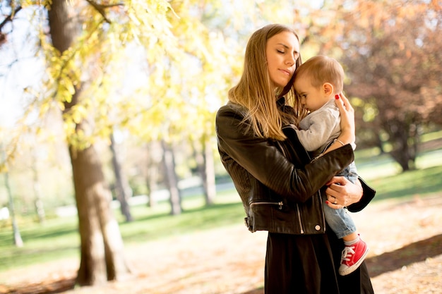 Joven madre y bebé en el parque de otoño