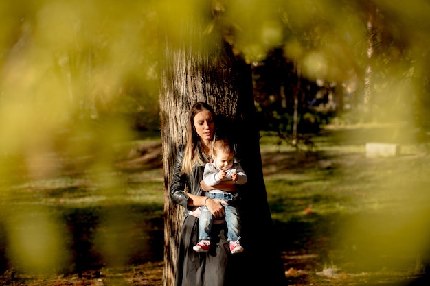 Joven madre y bebé en el parque de otoño