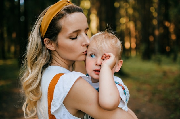 Joven madre besando a su hijo en el bosque